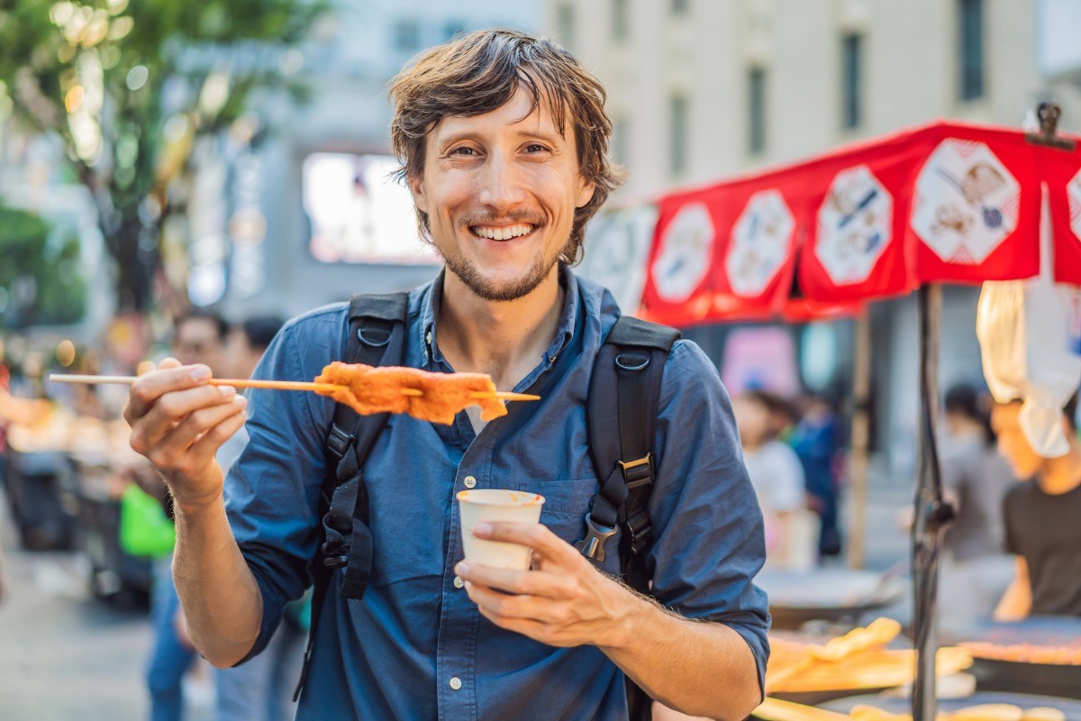 Man holding hot dog at outdoor street food market stall