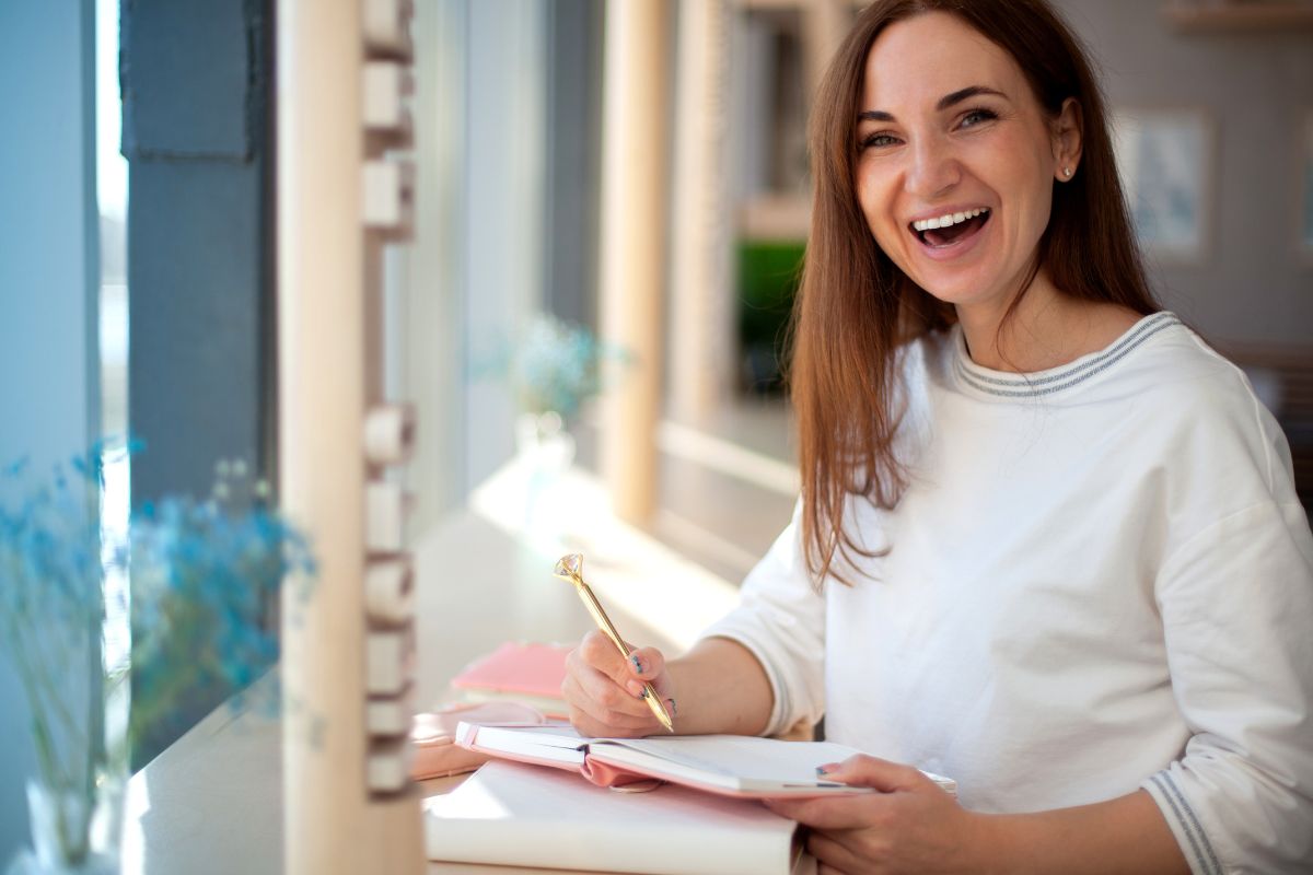 Packing List for a Healthy Smile Woman in white sweater writing in notebook at bright office desk